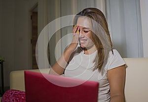 Young attractive and natural latin woman in pajamas pants relaxed on couch networking using laptop computer shopping online