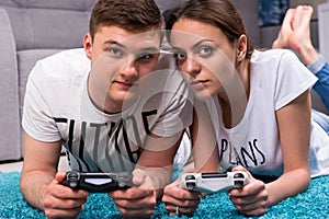 Young attractive pair lying on a rug playing video games
