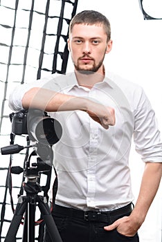 Young attractive photographer leaning on tripod