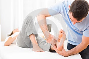 Young attractive physiotherapist doing reflexology on a patient