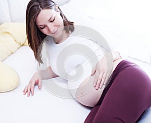 Young attractive pregnant woman in bed holding her tummy relaxing.