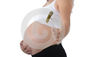 Young attractive pregnant woman holding her big belly in one hand and fork with pickle