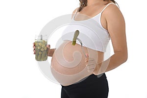 Young attractive pregnant woman showing big belly holding olives jar and fork with pickle