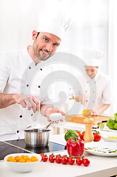 Young attractive professional chef cooking in his kitchen