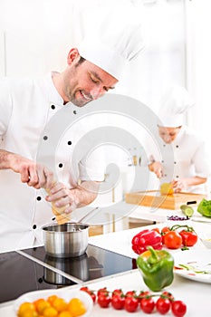 Young attractive professional chef cooking in his kitchen