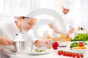 Young attractive professional chef cooking in his kitchen