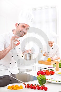 Young attractive professional chef cooking in his kitchen