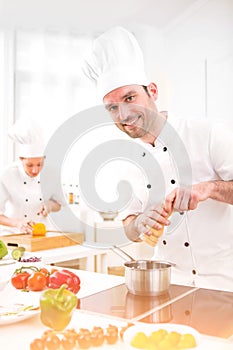 Young attractive professional chef cooking in his kitchen