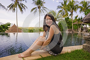 Young attractive and relaxed Asian Chinese woman enjoying happy beautiful view from tropical resort infinity pool in exotic luxury