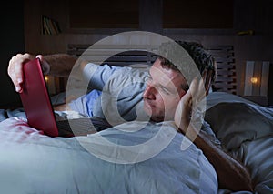 Young attractive and relaxed man networking at home lying comfortable on bed late night happy watching movie on laptop computer or