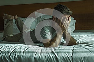 Young attractive sad and depressed man crying helpless on bed at home bedroom feeling overwhelmed and desperate suffering
