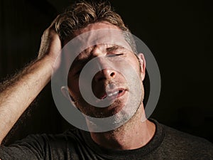 Young attractive and sad man suffering depression and headache with hand on his tempo head in stress looking worried and sick iso