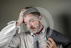 Young attractive sad and worried businessman in lose tie and messy look feeling depressed and stressed in overwhelmed face