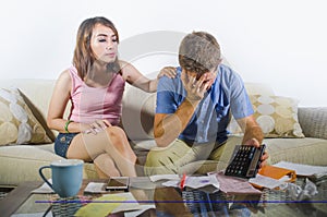 Young attractive sad and worried couple accounting together in financial stress at home couch in domestic finance problem