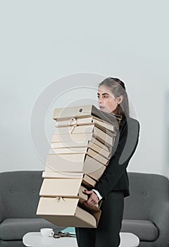 Young attractive secretary woman in a busy modern workplace in office. Pretty accountant girl holding many folders with
