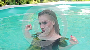 Young attractive, sexy woman in a black swimsuit posing seductively in the pool. Relaxation in the water in hot summer weather