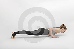 Young attractive slim fitness girl in bodysuit doing exercises on white background. Beautiful sporty yogi woman practice yoga