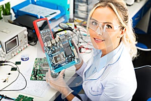 Female electronic engineer holding computer motherboard in hands photo