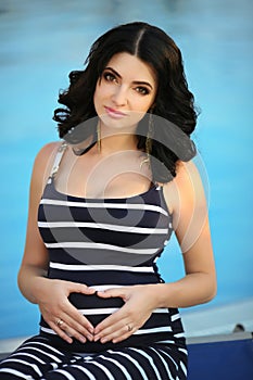 Young attractive smiling pregnant woman relaxing by swimming poo