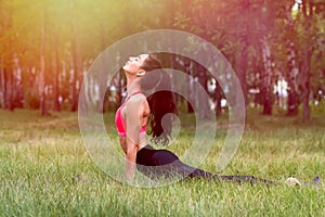 Young attractive smiling toned brunette woman stretching outside in a park. Healthy lifestyle concept