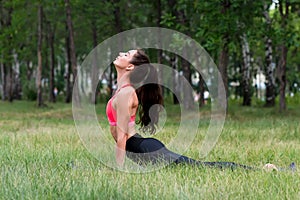 Young attractive smiling toned brunette woman stretching outside in a park. Healthy lifestyle concept