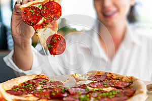 Young attractive smiling woman eating pizza at street cafe. Cheat meal. Cheat day