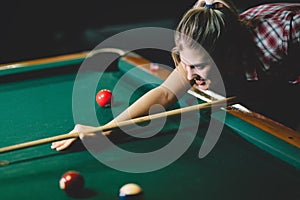 Young attractive woman playing pool in bar