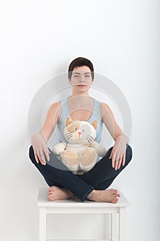 Young attractive smiling woman practicing yoga, sitting in Half Lotus exercise Ardha Padmasana pose, working out wearing