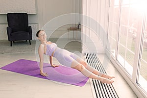 Young attractive smiling woman practicing yoga, working out, wearing sportswear, bra, home