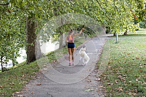 Young attractive sport girl running with dog in park