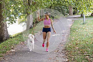 Young attractive sport girl running with dog in park