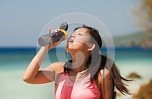 Young attractive sport runner woman exhausted after hard running workout on the beach drinking water recovering energy and fluids