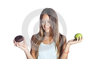 Young attractive sport woman holding apple and chocolate donut in her hands in healthy fruit versus sweet junk food temptation in