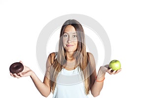 Young attractive sport woman holding apple and chocolate donut in her hands in healthy fruit versus sweet junk food temptation