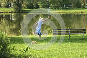 Young attractive sport woman playing badminton in the park on a bright sunny day blue dress hat Picnic