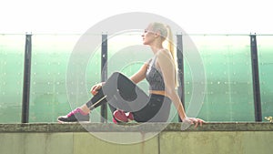 Young, attractive and sporty blond girl in sportswear listening to the music and relaxing outdoor. Healthcare, sport