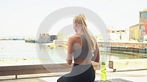 Young, attractive and sporty blond girl in sportswear listening to the music and relaxing outdoor. Healthcare, sport