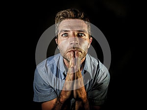 Young attractive stressed man with hands palms together praying and wishing success to come looking concentrated hoping for good l