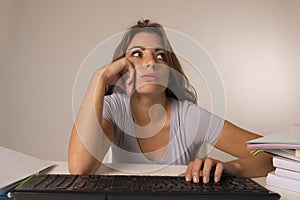 Young attractive student girl or working woman sitting at computer desk in stress looking tired exhausted and boring