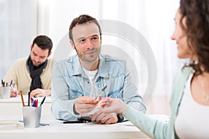 Young attractive student lend a pen to classmate