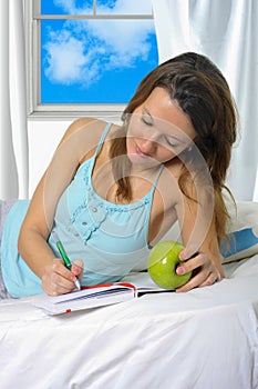 Young attractive student woman with apple in nightgown