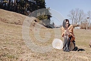 Young attractive stylish girl on nature on forest background with phone on a sunny day. outdoor holidays and dependence on