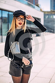 Young attractive stylish smiling woman having fun in city , positive, emotional, long hair, wearing leather shorts and black