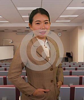 Young attractive and successful Asian Chinese business woman in auditorium at corporate training event or seminar giving