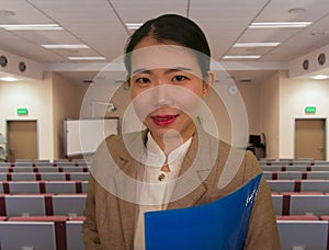 Young attractive and successful Asian Chinese business woman in auditorium at corporate training event or seminar giving