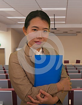 Young attractive and successful Asian Korean business woman in auditorium at corporate training event or seminar giving motivation