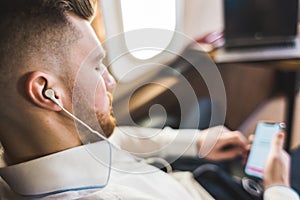 Young attractive and successful businessman is resting and listening to music works while sitting in the chair of his