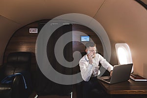 Young attractive and successful businessman talking on the phone and working while sitting in the chair of his private