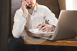 Young attractive and successful businessman talking on the phone and working while sitting in the chair of his private