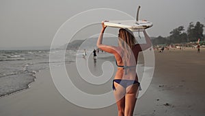 Young attractive surfer girl in bikin on the beach with surf